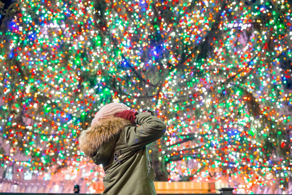 Woman admiring massive Rockefeller-style Christmas light tree